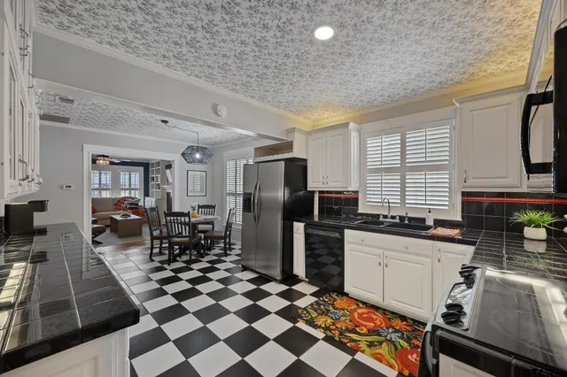 a kitchen with stainless steel appliances granite countertop a sink a stove a chimney a refrigerator and cabinets