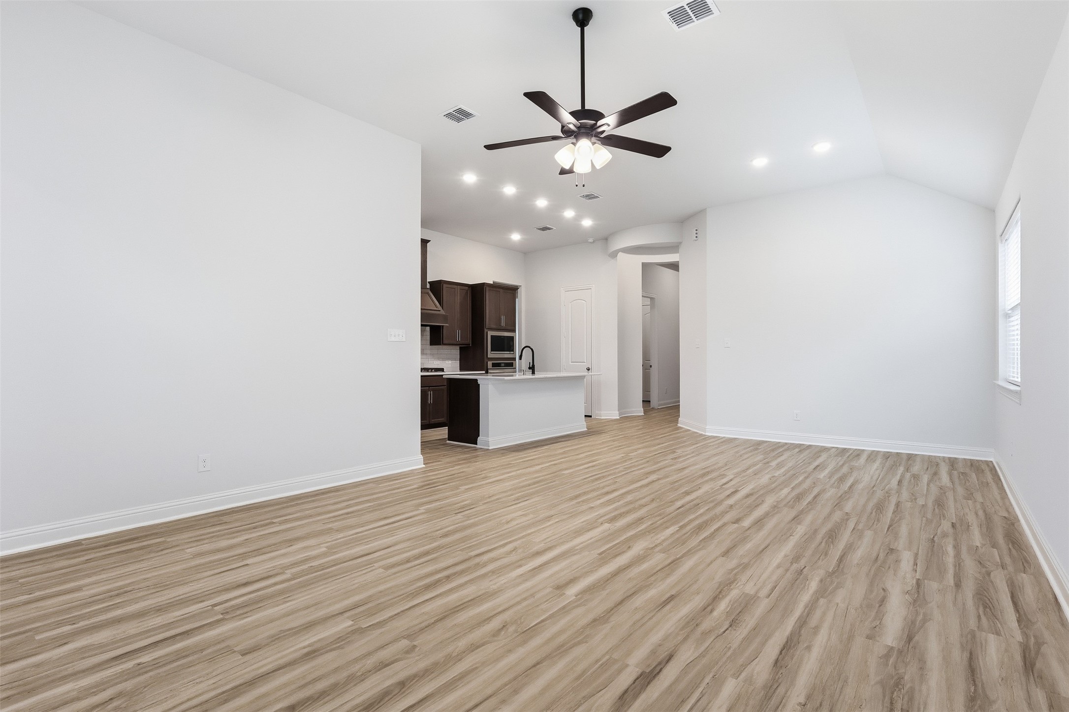 3006 Myrtle Bch Lane League City, TX 77573 - Photo 15 of 21 a view of empty room with wooden floor ceiling fan and kitchen view