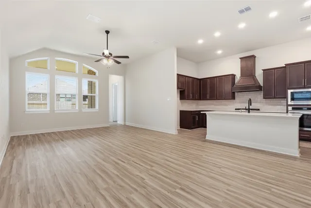 an empty room with wooden floor cabinet and windows