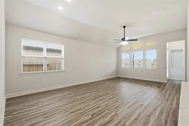 an empty room with chandelier fan and windows