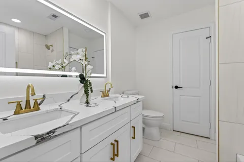 a view of a hallway with wooden floor and a bathroom
