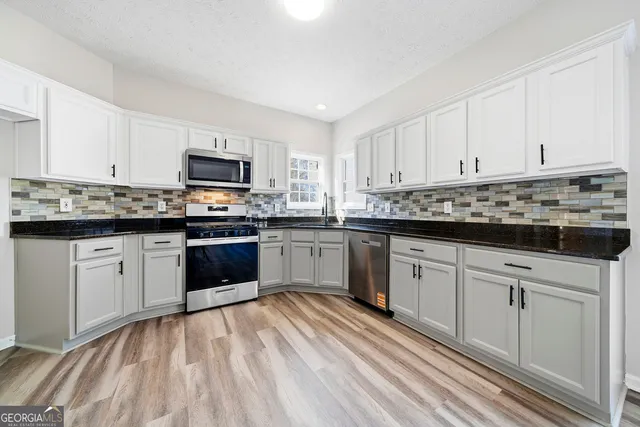 a kitchen with stainless steel appliances granite countertop a stove top oven and sink