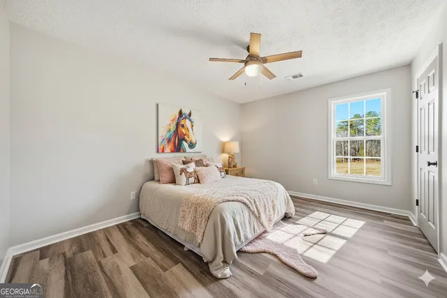 an empty room with wooden floor fireplace and windows