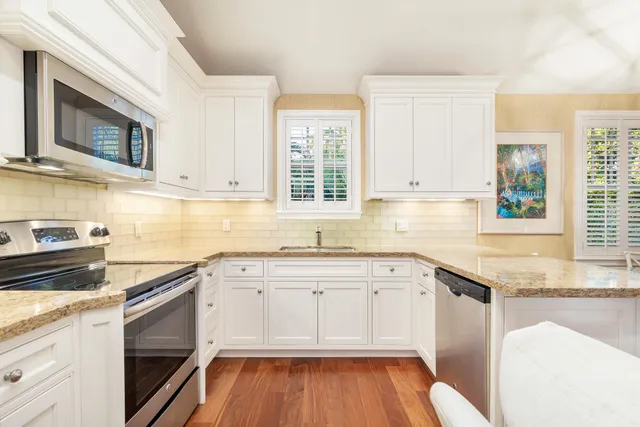 a kitchen with granite countertop white cabinets sink and window