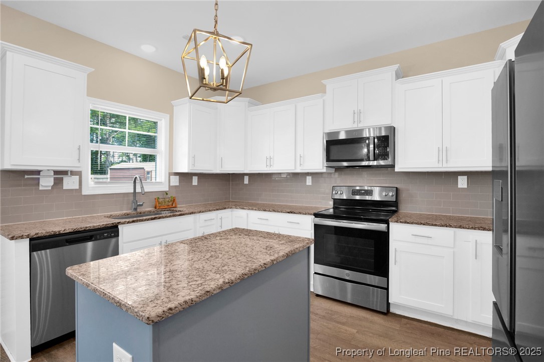 405 Shelton Beard Road Stedman, NC 28391 - Photo 11 of 36 a kitchen with stainless steel appliances granite countertop a sink dishwasher stove and microwave with wooden floor