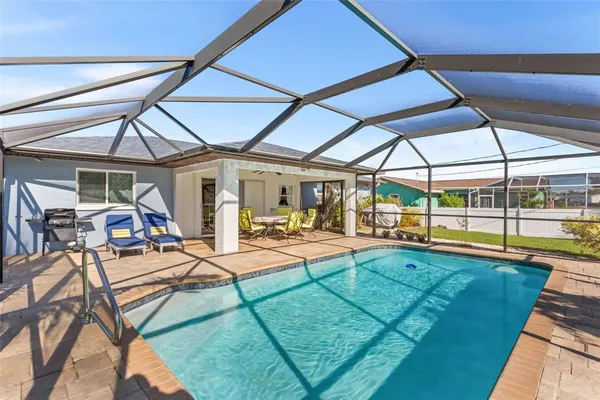 a view of a swimming pool with chairs and tables in the patio