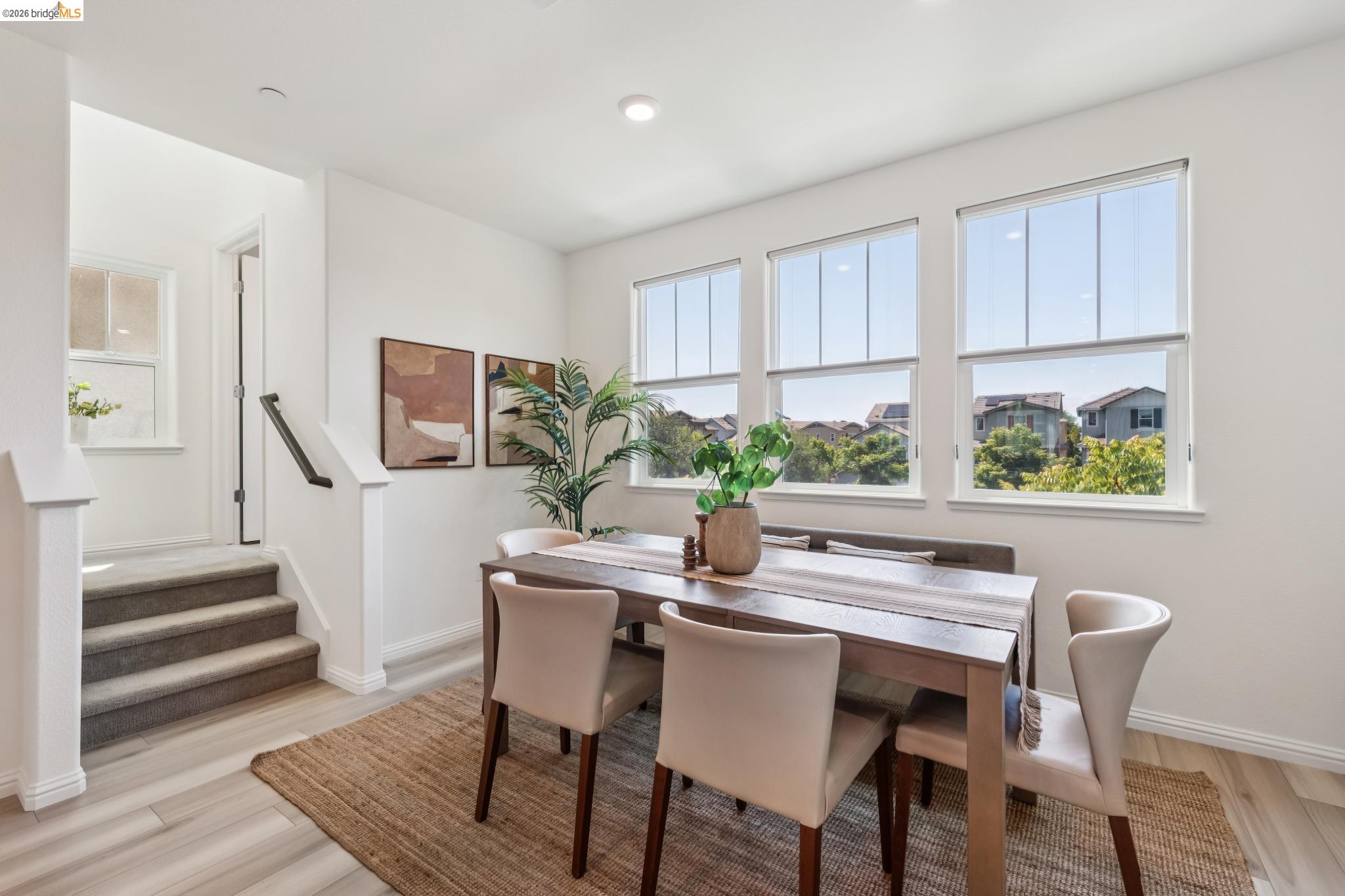 24157 Amaranth Loop Hayward, CA 94541 - Photo 28 of 63 Dining area featuring three large windows, wood-finish flooring, and a carpeted staircase with a dark handrail