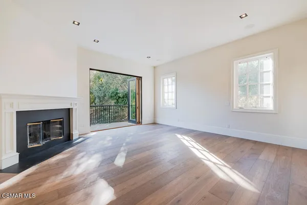 a view of empty room with wooden floor and fireplace