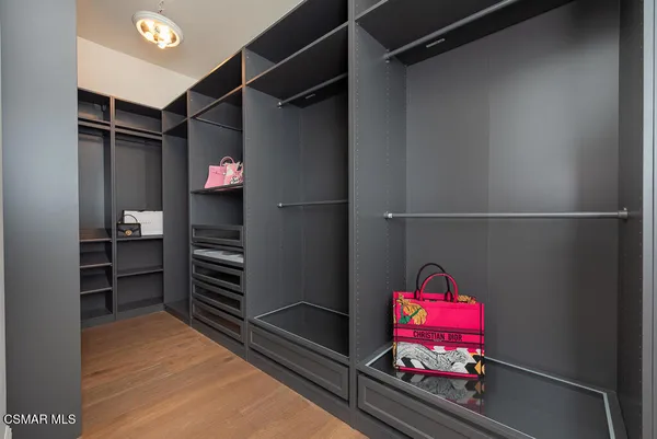 a view of walk in closet with clothes and shoes