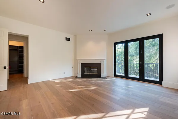 a view of an empty room with wooden floor fireplace and a window