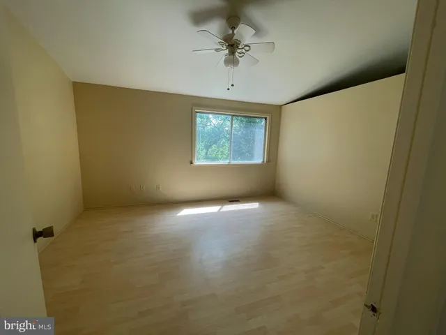 en empty room with windows and ceiling fan