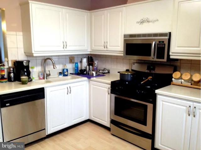 a kitchen with stainless steel appliances a stove a microwave a sink and cabinets