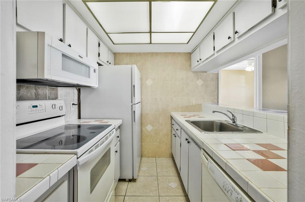 4345 27th Court Southwest, Unit 204 Naples, FL 34116 - Photo 11 of 25 a kitchen with stainless steel appliances granite countertop a sink stove and refrigerator