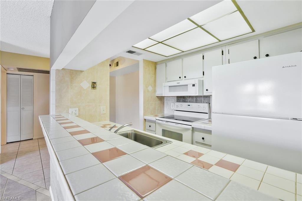 4345 27th Court Southwest, Unit 204 Naples, FL 34116 - Photo 12 of 25 a kitchen with a sink appliances and cabinets
