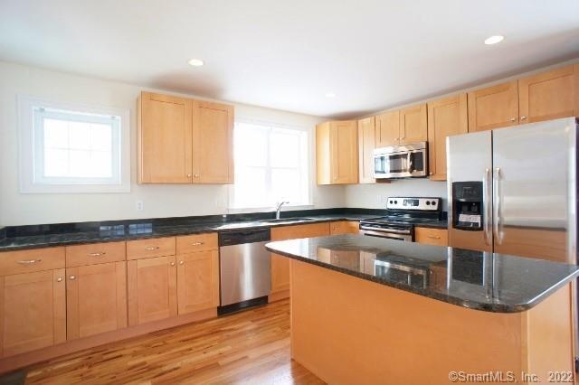 a kitchen with stainless steel appliances granite countertop a sink a stove and a refrigerator