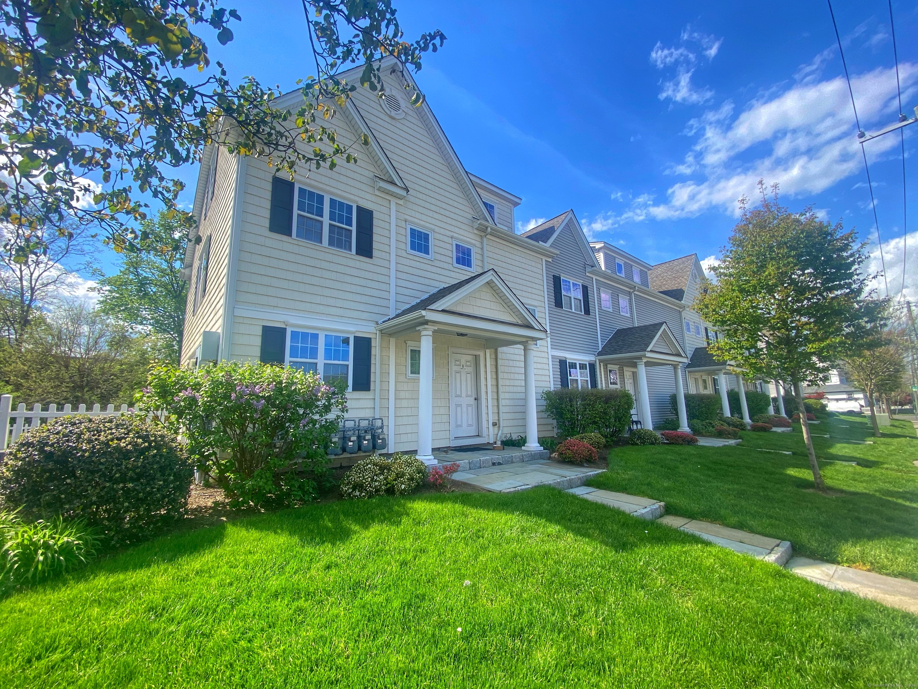 15 Arch Street, Unit B8 Norwalk, CT 06850 - Photo 9 of 10 a view of a yard in front of a brick house with plants and large trees