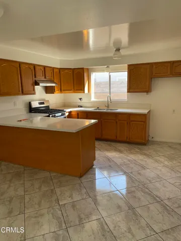 a large kitchen with granite countertop a stove a sink and a microwave