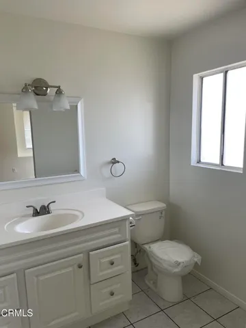 a bathroom with a toilet a sink a mirror and window