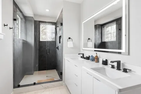a bathroom with a double vanity sink mirror and shower
