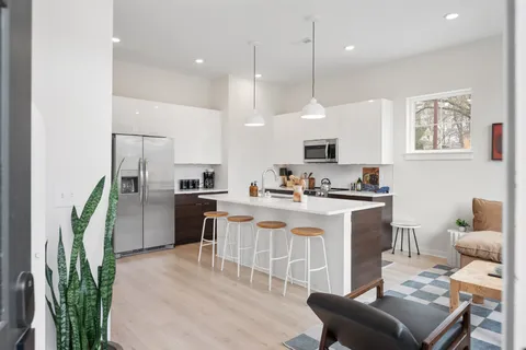 a kitchen with kitchen island a stove a sink a oven a dining table and chairs