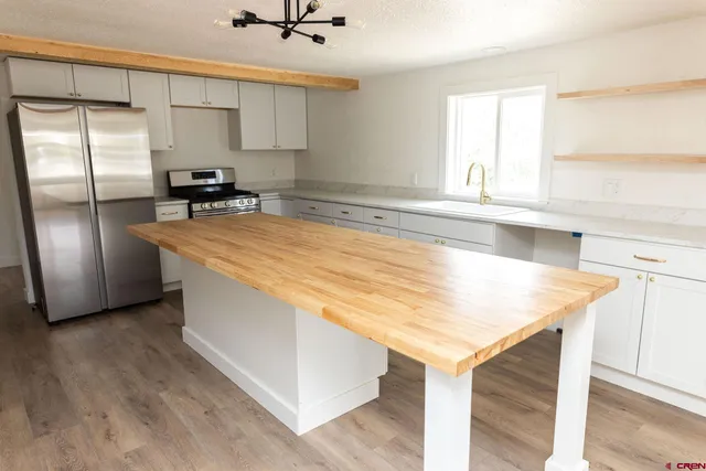 a kitchen with stainless steel appliances granite countertop a sink a stove and a refrigerator