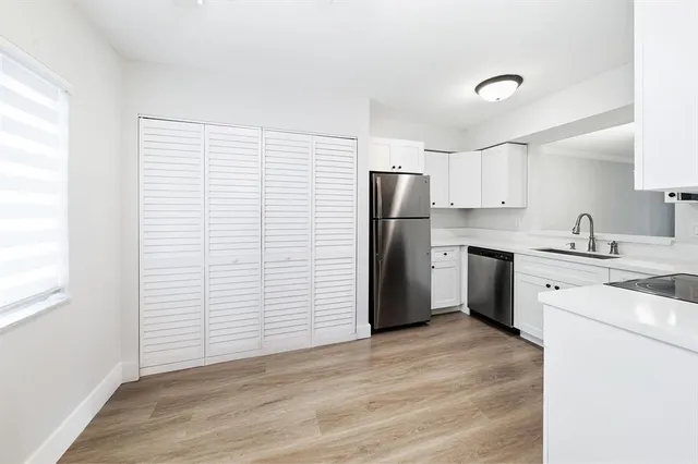 a kitchen with a sink stainless steel appliances and white cabinets