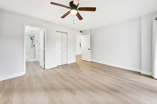 a view of empty room with wooden floor and fan