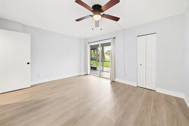 an empty room with wooden floor and a ceiling fan