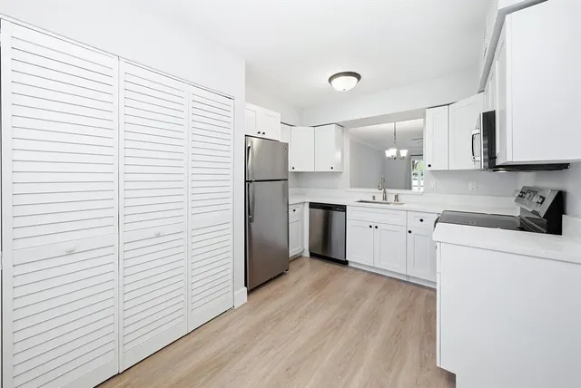a kitchen with a white wooden cabinets sink and white appliances