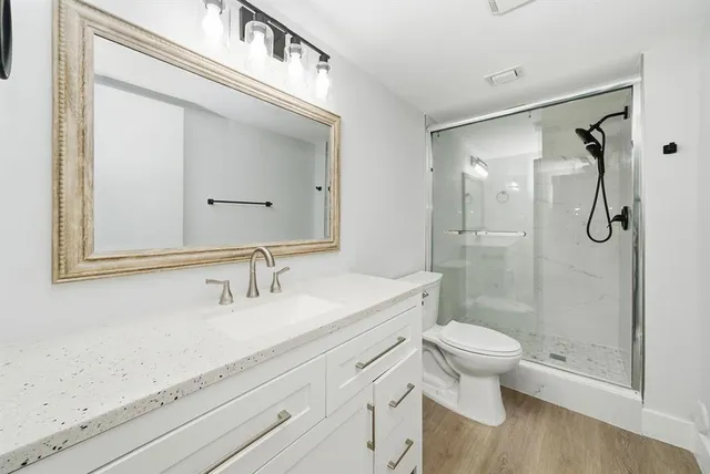 a bathroom with a shower sink vanity mirror and toilet