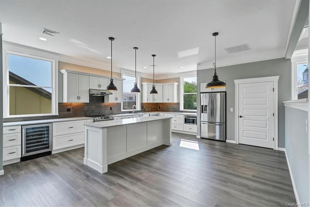a kitchen with stainless steel appliances a stove top oven a sink cabinets and wooden floor
