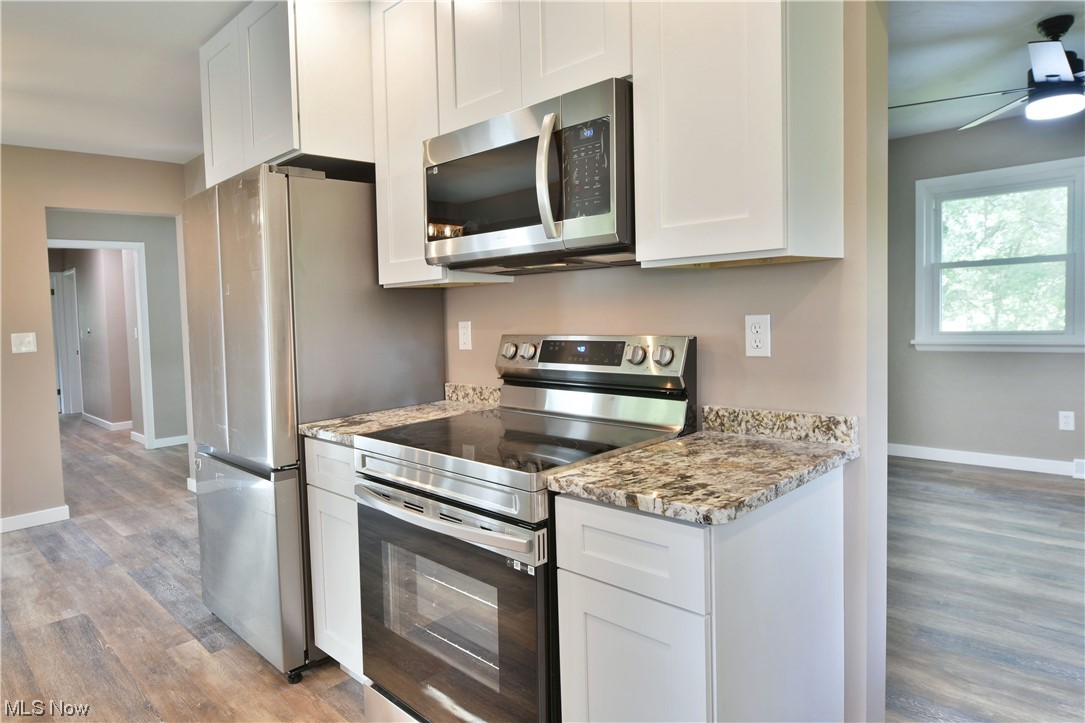 5480 Phillips Rice Road Cortland, OH 44410 - Photo 2 of 35 Kitchen featuring stainless steel appliances, white cabinetry, hardwood floors, light countertops, and ceiling fan