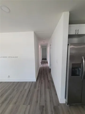 a view of a hallway to an empty room and wooden floor