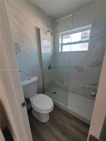 a white toilet sitting next to a shower