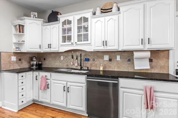 a kitchen with granite countertop white cabinets and sink