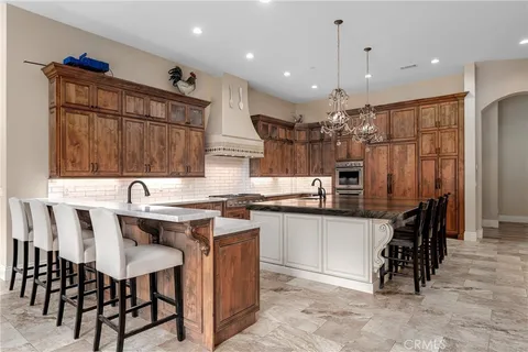 a kitchen with stainless steel appliances kitchen island granite countertop a table chairs sink and cabinets