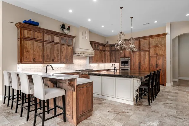 a kitchen with stainless steel appliances kitchen island granite countertop a table chairs sink and cabinets