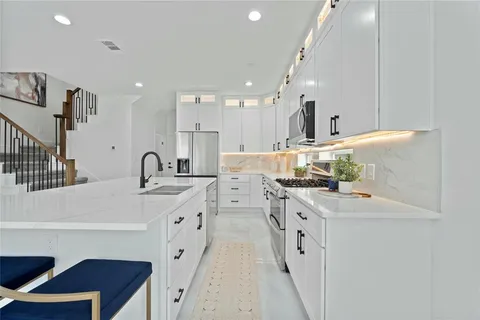 a large white kitchen with stainless steel appliances and white cabinets