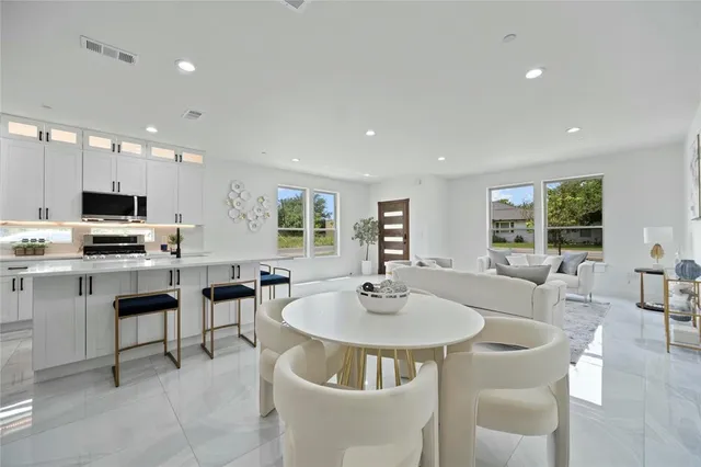 a kitchen with stainless steel appliances kitchen island granite countertop a sink a stove a dining table and chairs