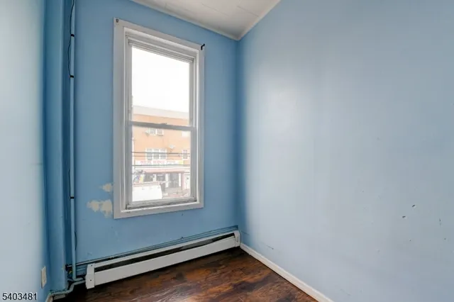 a view of an empty room with wooden floor and closet