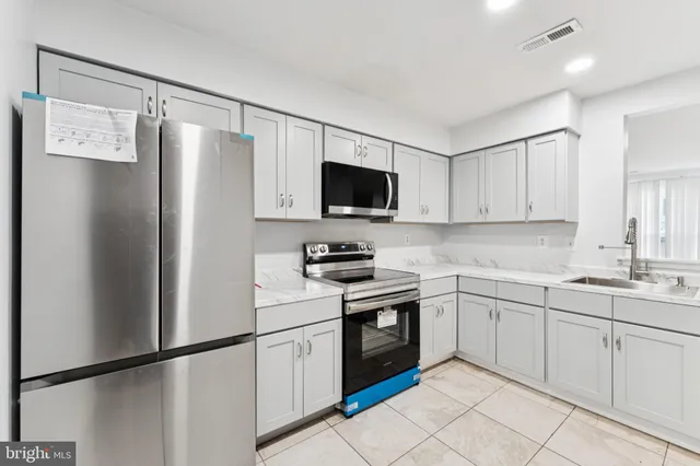 a kitchen with white cabinets stainless steel appliances and a sink