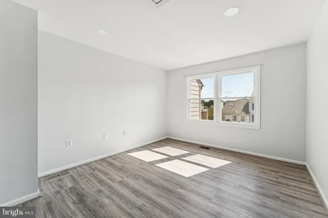 an empty room with wooden floor windows and cabinet