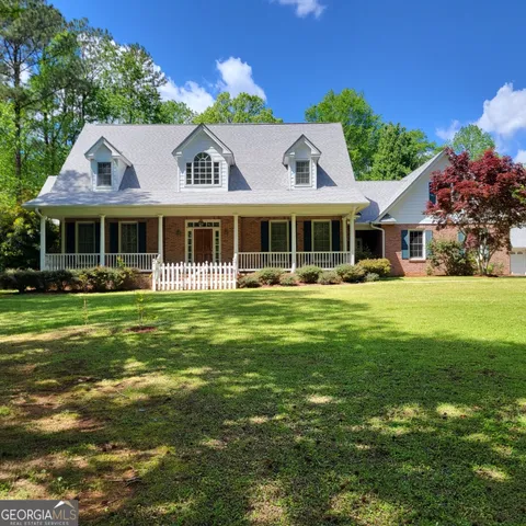 a front view of a house with garden and trees