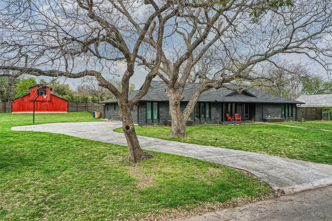 a view of a brick house with a yard and large tree