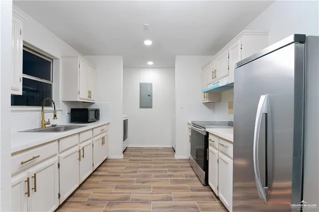 a large kitchen with a large counter top stainless steel appliances and cabinets