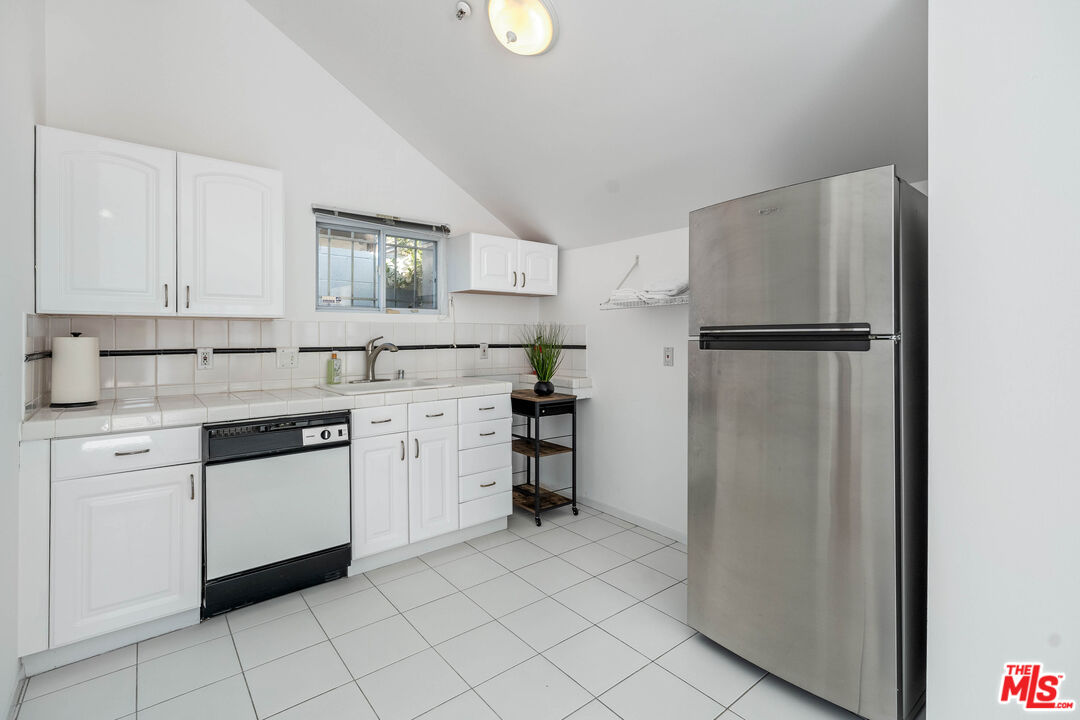 140 North Carson Road Beverly Hills, CA 90211 - Photo 22 of 28 a kitchen with white cabinets and white appliances
