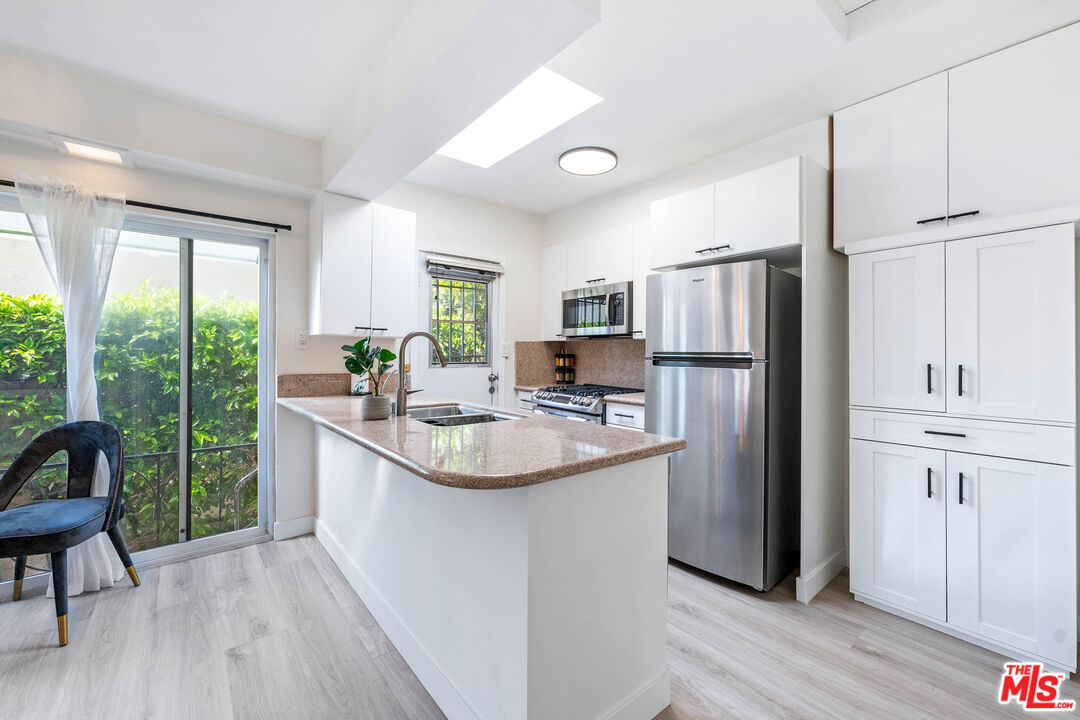 140 North Carson Road Beverly Hills, CA 90211 - Photo 6 of 28 a kitchen with stainless steel appliances granite countertop a refrigerator a sink a stove a refrigerator and white cabinets with wooden floor