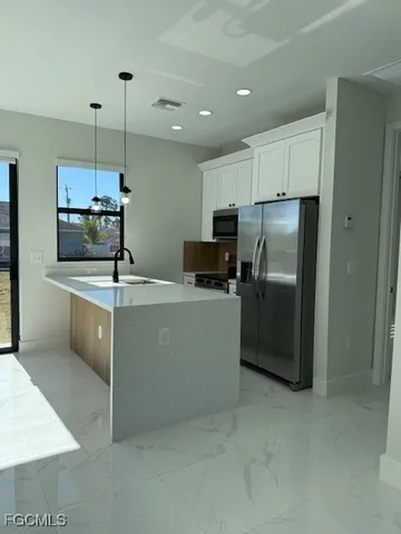a kitchen with kitchen island a counter top a sink stainless steel appliances and cabinets