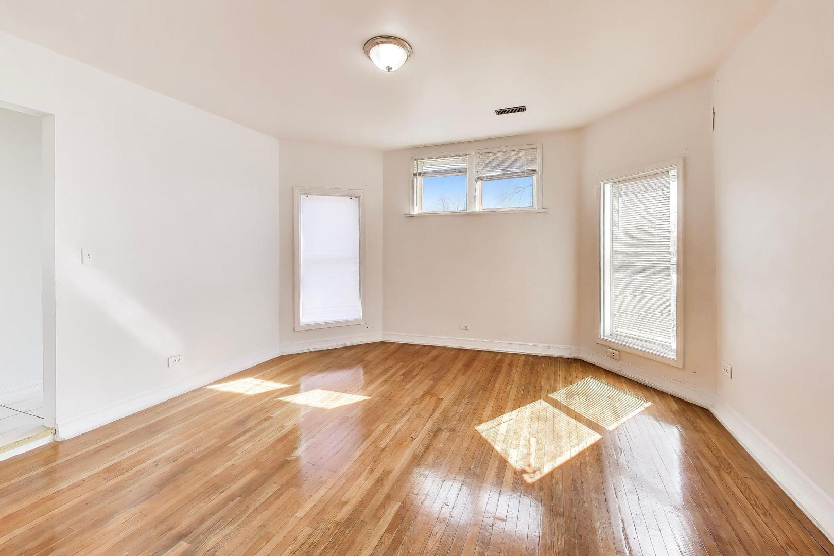6853 South Perry Avenue Chicago, IL 60621 - Photo 12 of 28 an empty room with wooden floor and windows