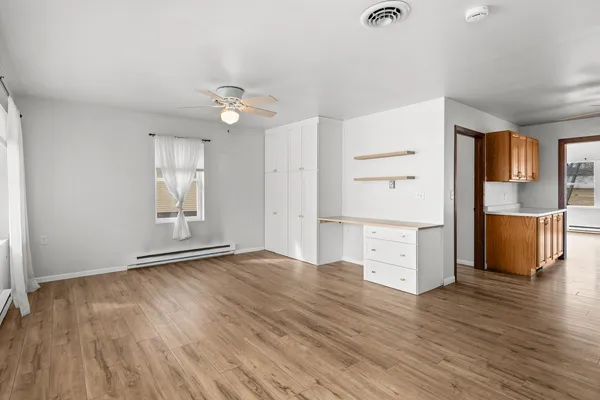 an empty room with wooden floor closet and windows